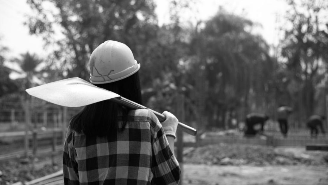 Construction workers carrying a shovel to the construction site