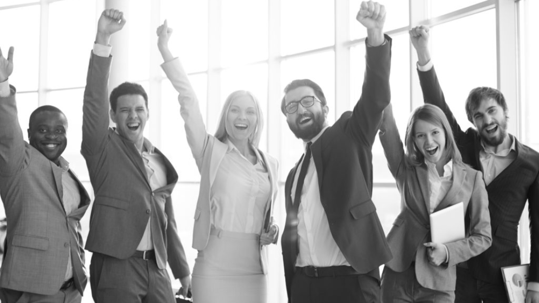 Group of ecstatic business partners looking at camera with raised arms